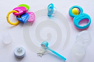 Baby milk powder, baby bottle and children`s toys on a light background flat lay