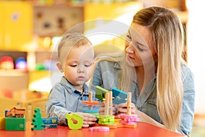 Baby minder playing with kid in nursery