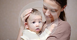 Baby in mom`s arms looking at the camera. Motherhood concept