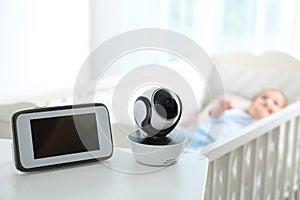 Baby monitor and camera on table near crib with child in room