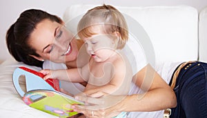 Baby, mother and book or reading on sofa with learning, relax and parenting in living room of home with smile. Family