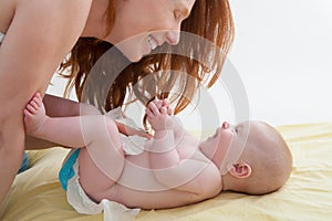 Baby with mother diapering and playing smiling