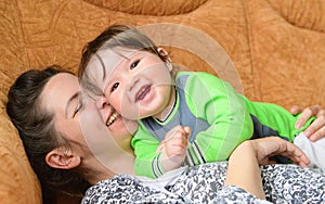 Baby with mother laugh. real emotions. Happy family. baby and mother play, kiss, tickle, laugh in bed. Happy family. baby and