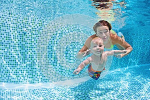 Baby with mother learn to swim underwater in swimming pool