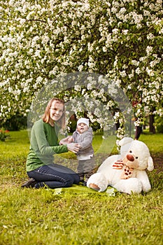 Baby with mother in the park in the rays of sunset. Toddler with mom on the nature outdoors. Backlight. Summertime family scene