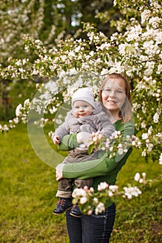 Baby with mother in the park in the rays of sunset. Toddler with mom on the nature outdoors. Backlight. Summertime family scene