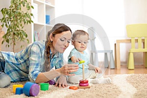 Baby and mother playing toy rings. Toddler kid plays pyramid, children early education