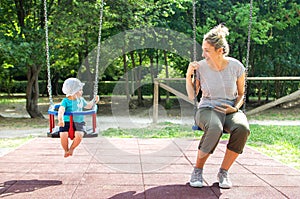 Baby mother swing playground looking each other photo
