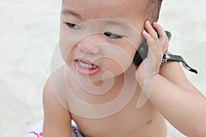 Baby murmuring on cellphone,grinnig,looking left.