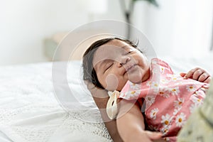 baby newborn daughter, is 1-months-old and is half Thai half Nigerian, sleeping well on the hands of father