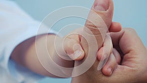 Baby newborn holding a mom hand. kid dream concept. close-up baby hand grabs finger of mother hand. newborn baby and mom