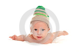 Baby newborn lying on her stomach on the bed in a funny knitted hat isolated on white background, the concept of choosing baby clo