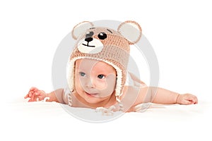 Baby newborn lying on her stomach on the bed in a funny knitted hat isolated on white background, the concept of choosing baby clo