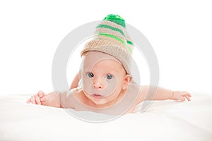 Baby newborn lying on her stomach on the bed in a funny knitted hat isolated on white background, the concept of choosing baby clo