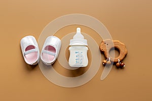 Baby newborn pink booties with bootle of milk and wooden toy