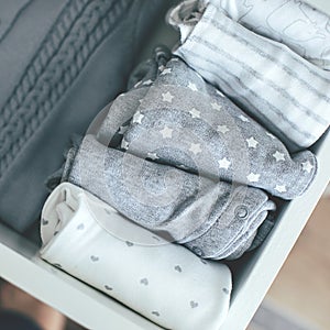 Baby or newborn things of white, blue, grey colors in drawer. Lady fly system, kondo konmary concept