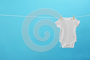 Baby onesie hanging on clothes line against background, space for text. Laundry day