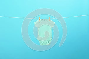 Baby onesie hanging on clothes line against blue background