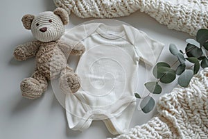 Baby onesie mockup with teddy bear and eucalyptus branch on white blanket, infant clothing template