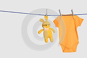 Baby onesie and toy bunny drying on laundry line against background