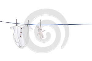 Baby onesie and toy bunny drying on line against white background