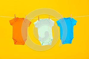 Baby onesies hanging on clothes line against background