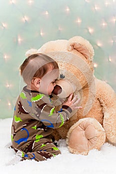 Baby in pajamas kissing teddy bear