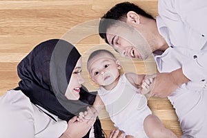 Baby and parents lying on wooden floor