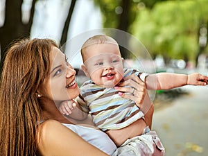 Baby in park outdoor. Kid on mom`s hands.