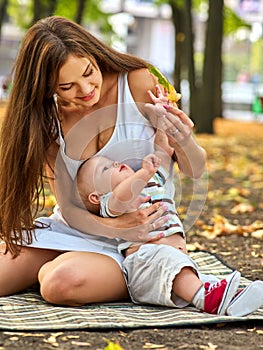 Baby in park outdoor. Kid on mom`s hands.