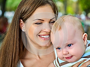 Baby in park outdoor. Kid on mom`s hands.