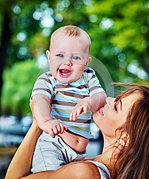 Baby in park outdoor. Kid on mom`s hands.