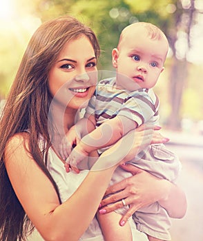 Baby in park outdoor. Kid on mom`s hands.