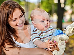 Baby in park outdoor. Kid with toy on mom`s hands.