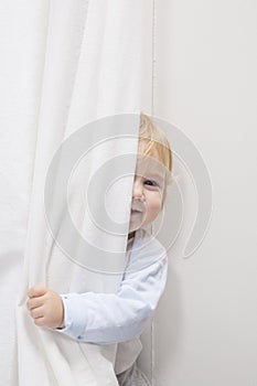 Baby peeking behind curtain