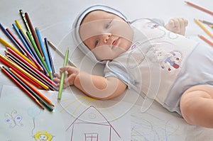 A baby with pencils. The child draws.