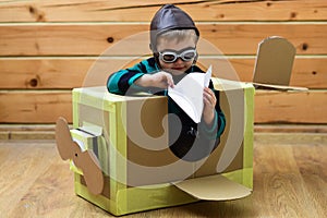 Baby play in cardboard plane, childhood. Pilot travel, airdrome, imagination. Kid, pilot school, innovation. Dream kids photo