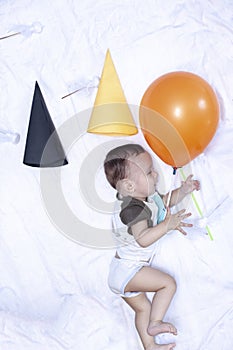 Baby playing with a balloon. First birthday. Baby boy lying at his bed