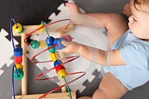Baby playing with educational toy in nursery. Learning colorful wooden toy.developing toy. The labyrinth of wooden beads.geometric