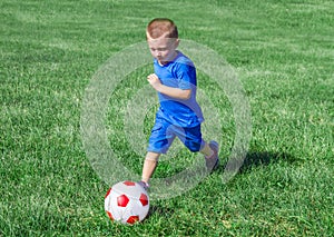 Baby playing football in the meadow