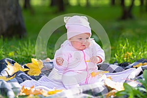 Baby playing on picnic rug amongst autumn leaves