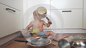 baby playing pots in the kitchen on the floor. happy family kid dream concept. baby scattered pots play dabble sitting