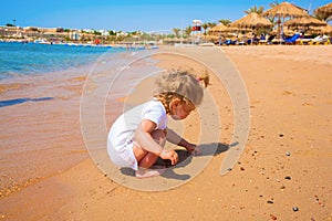 Baby playing with sand by the sea