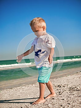 Baby playing on the seaside in summertimes. Summer rest concept. Lilltle boy having fun with the sand. Happy childhood