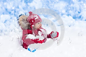 Baby playing with snow in winter.