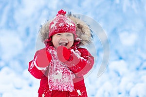 Baby playing with snow in winter.