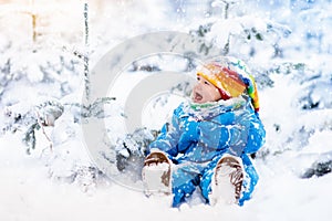 Baby playing with snow in winter. Child in snowy park.