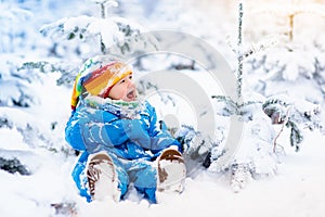 Baby playing with snow in winter. Child in snowy park.