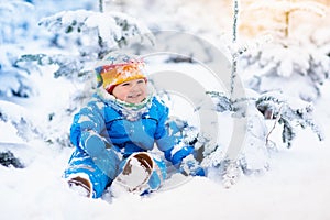 Baby playing with snow in winter. Child in snowy park.