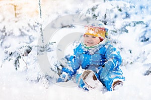 Baby playing with snow in winter. Child in snowy park.